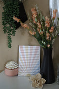Pastel sunburst lined notepad displayed against a neutral background with florals