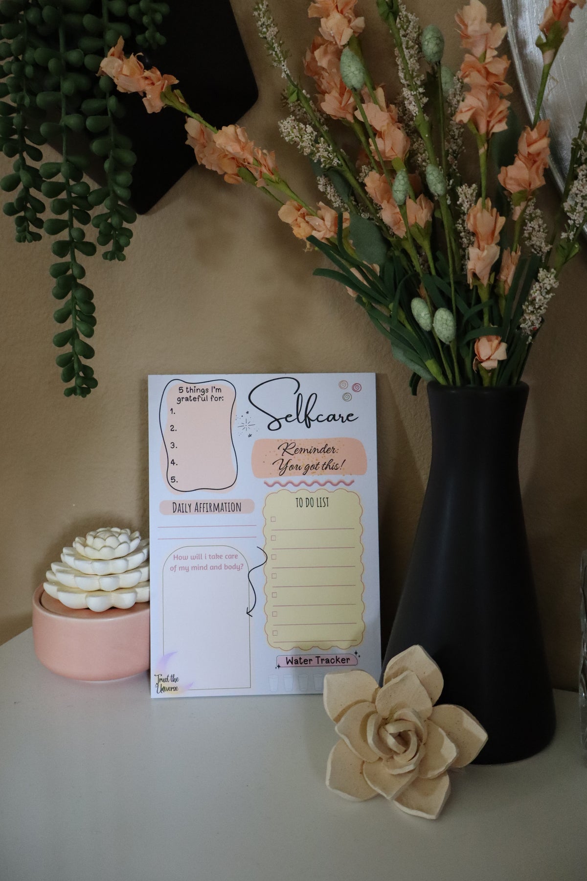 Selfcare daily planner notepad displayed with florals and succulents