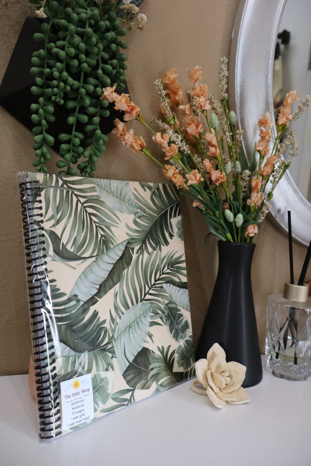 Tropical palm leaf softcover spiral notebook displayed with florals and succulents