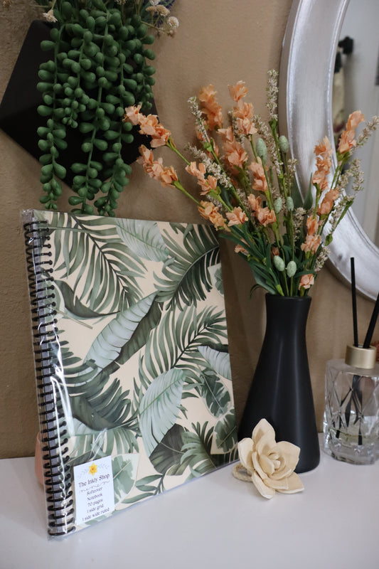 Tropical palm leaf softcover spiral notebook displayed with florals and succulents