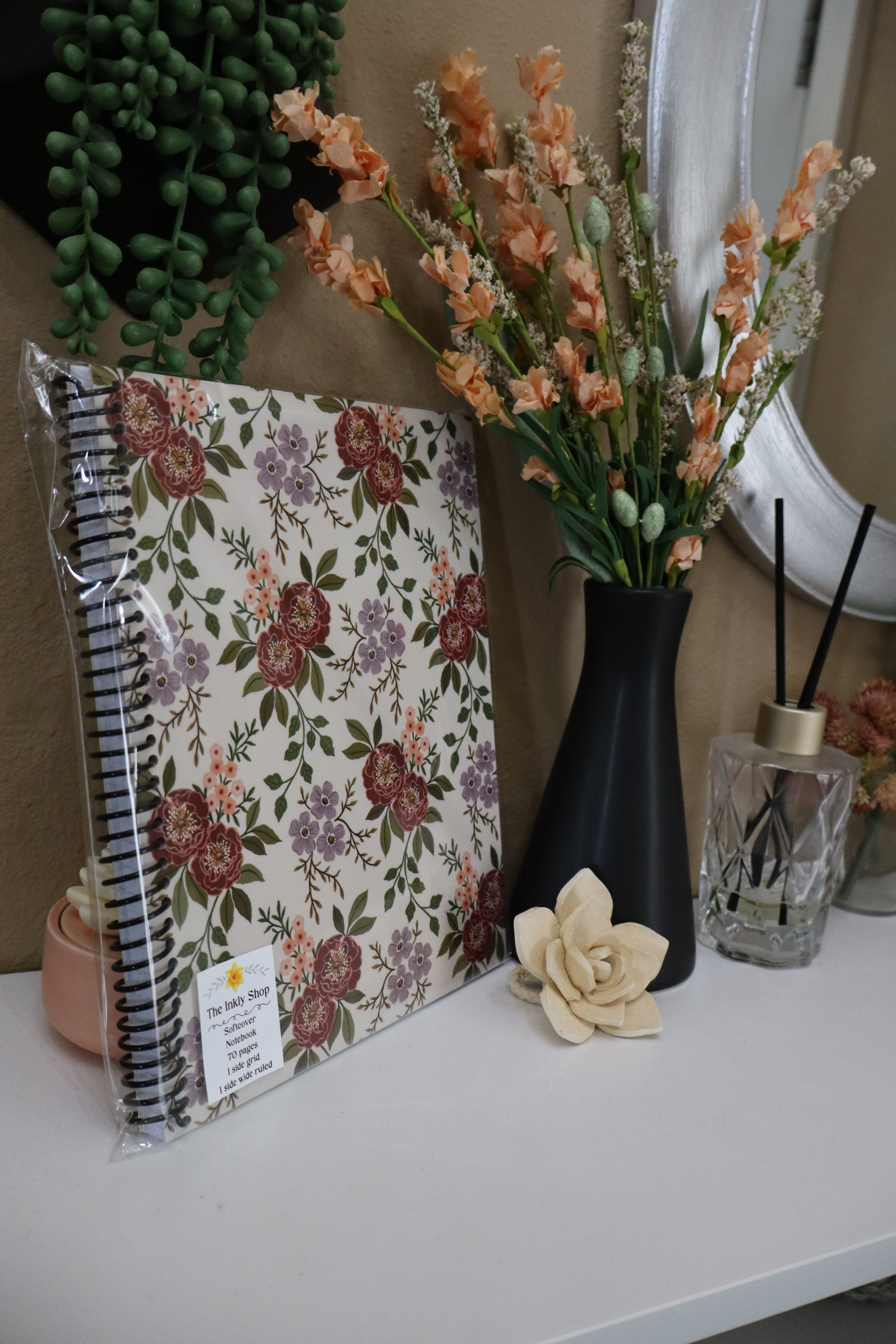 Vintage floral softcover spiral notebook displayed with peach flowers and succulents