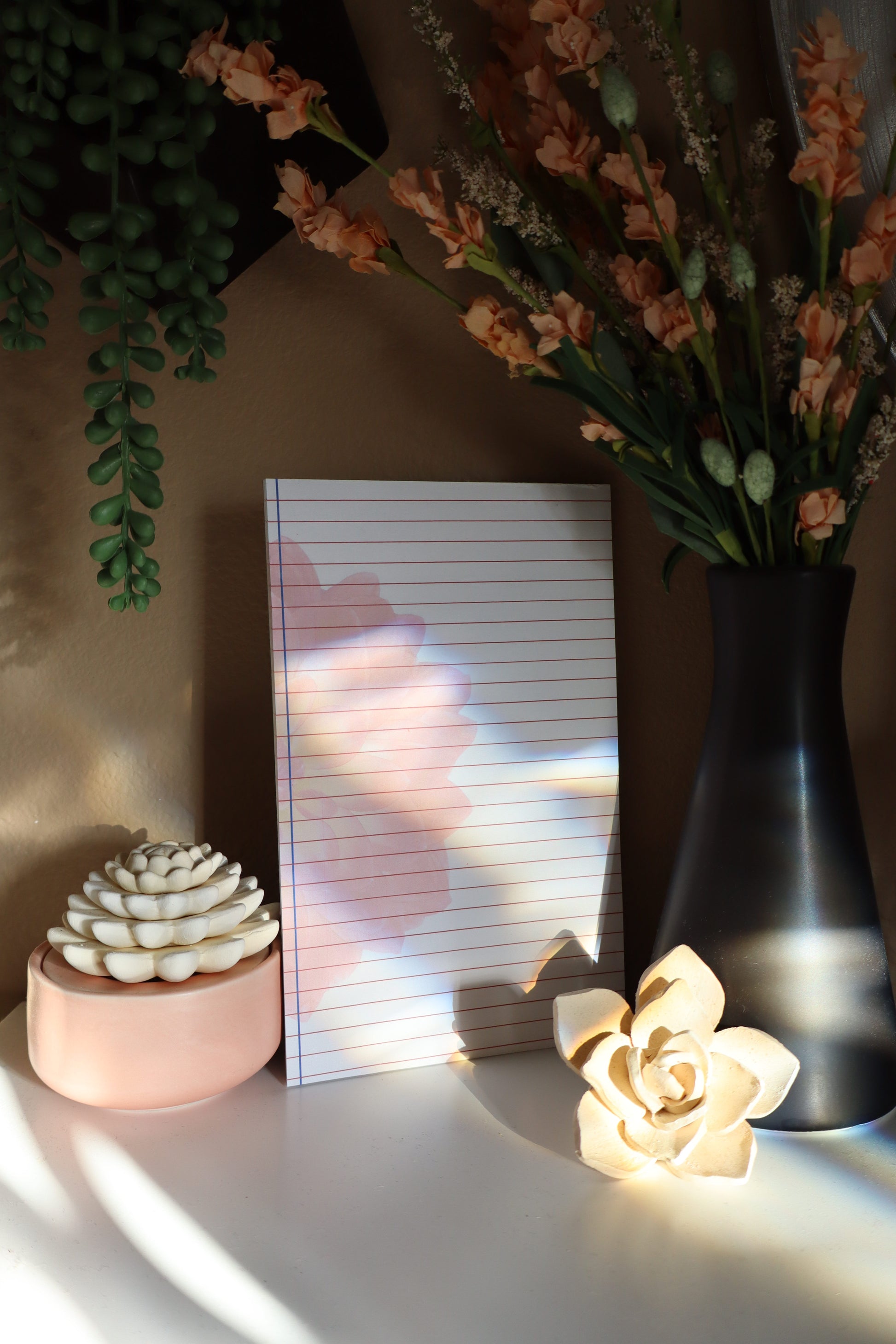 Lined notepad with moody lighting and floral styling