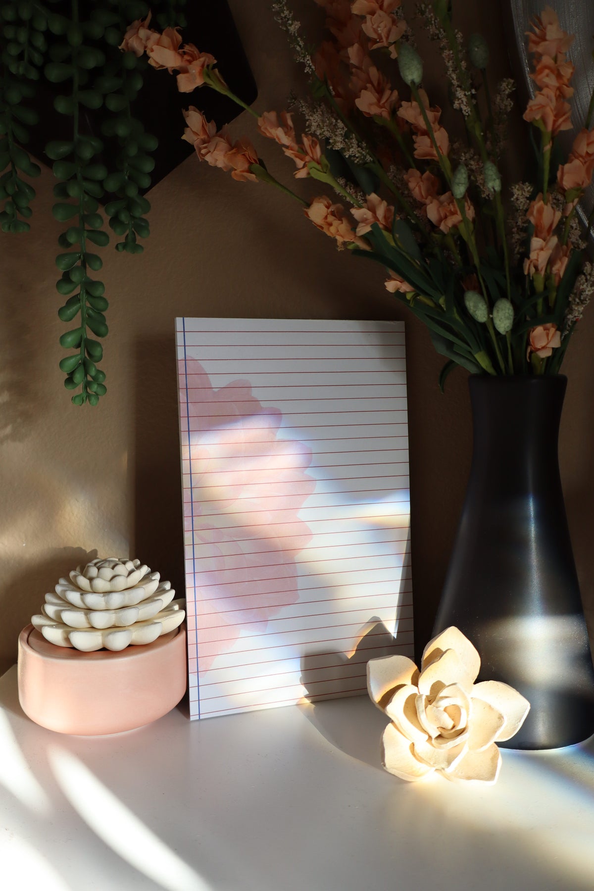 Lined notepad with moody lighting and floral styling